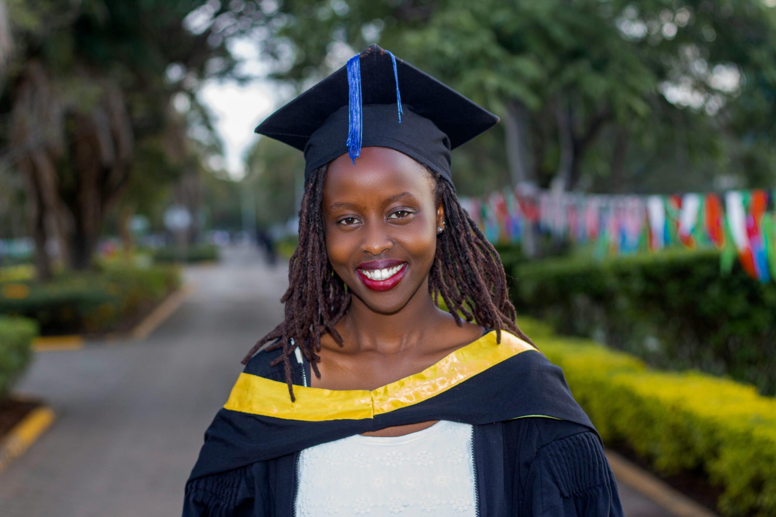 Joyful graduate wearing cap and gown at an outdoor ceremony.