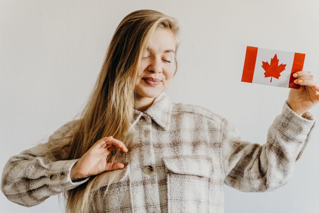 Blonde woman with closed eyes holding Canada flag symbolizing pride and celebration.